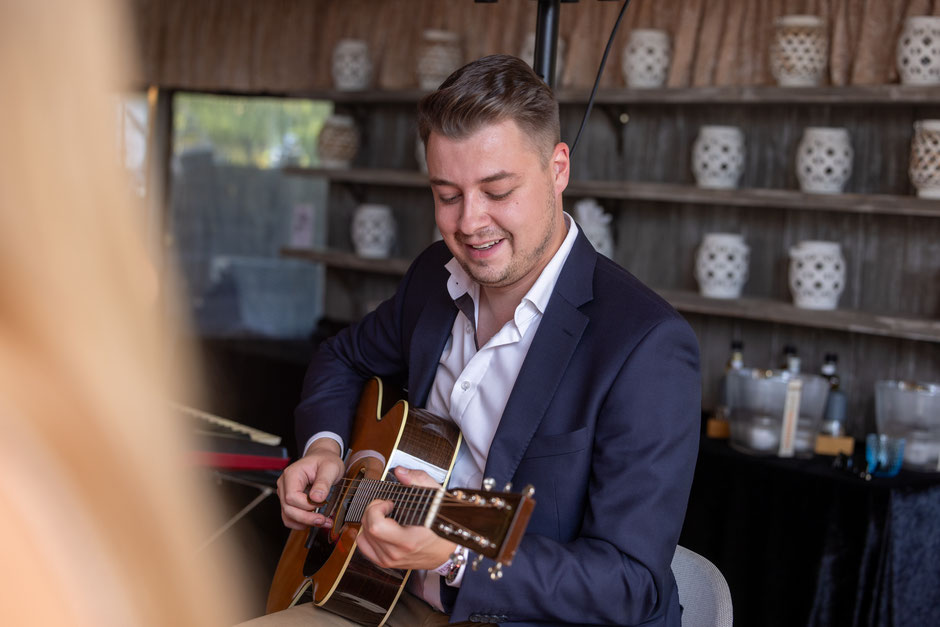 A picture of our artist Julian Wolf playing the guitar in front of an audience.