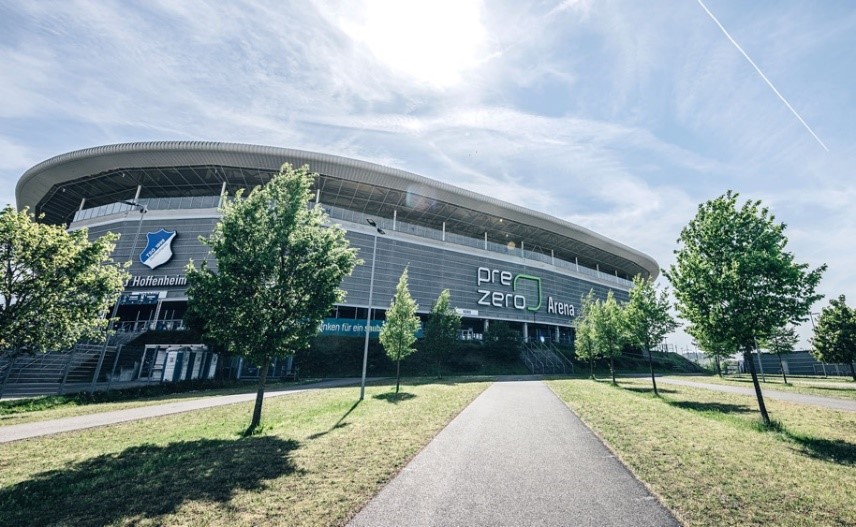 Zu sehen ist die PreZero Arena des Bundesligisten TSG Hoffenheim. Davor ist ein Weg mit Bäumen.