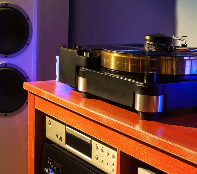 You can see a black record player lying on a brown wooden table.